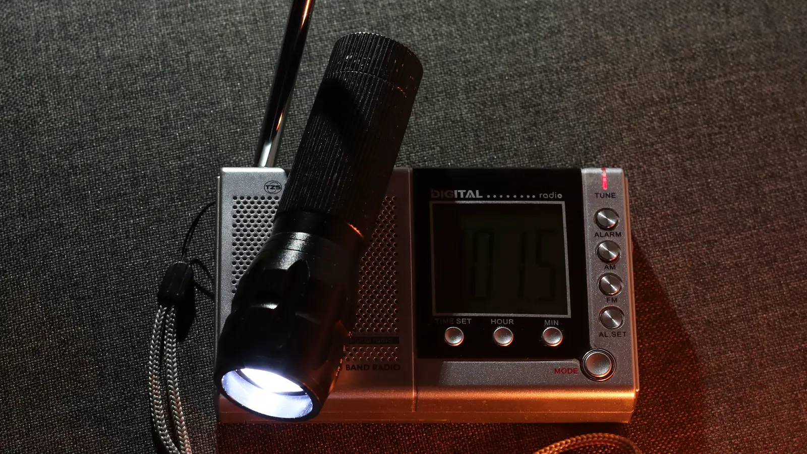 A lit torch resting on a battery radio in a dark room